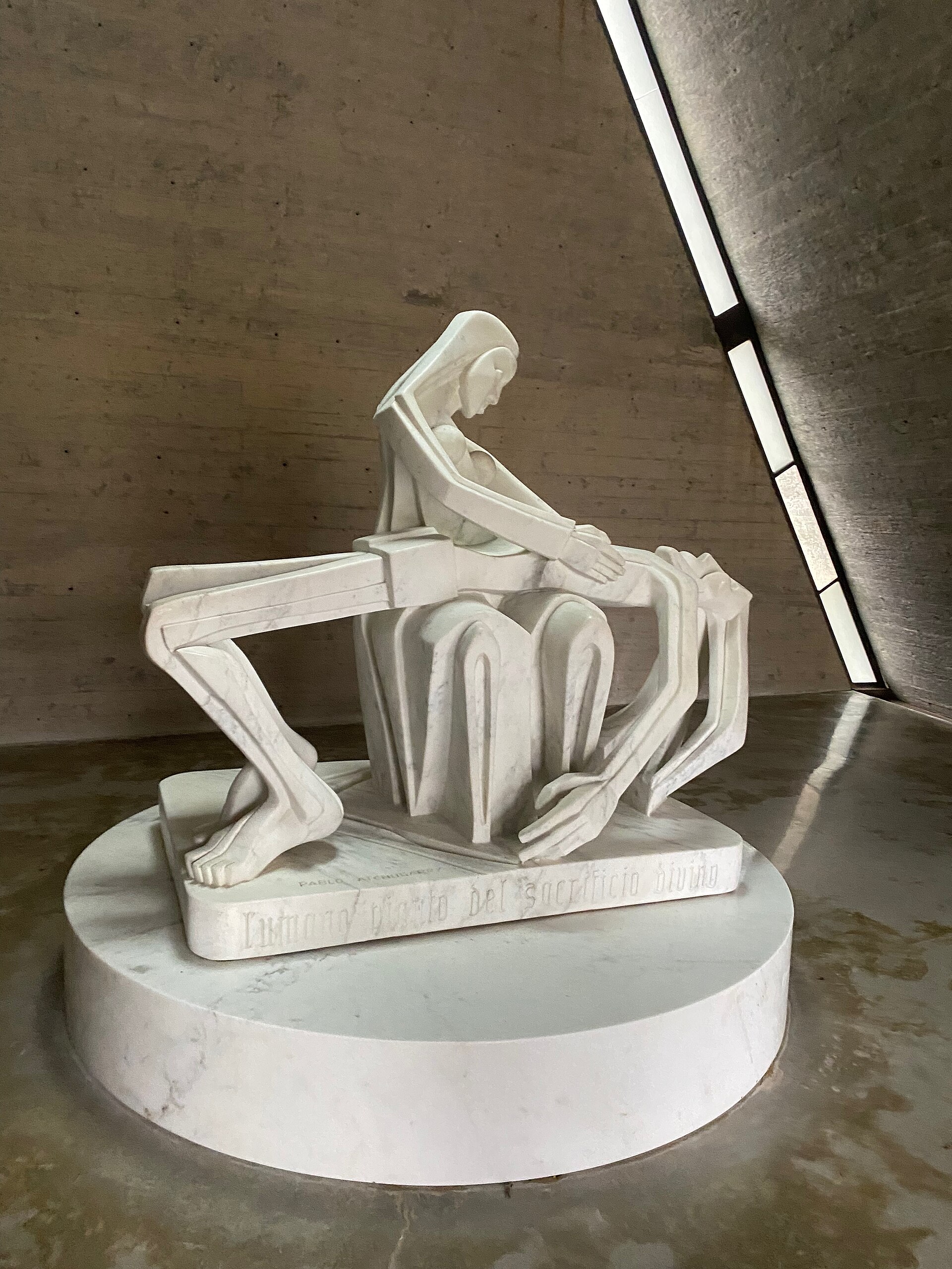 Pablo Atchugarry, La Pietà: scultura in marmo bianco su basamento circolare in una cappella