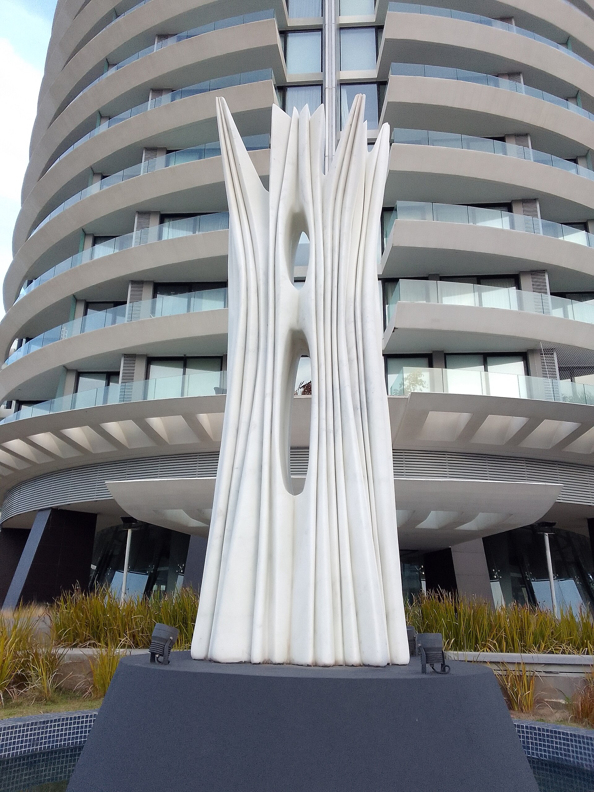 Pablo Atchugarry, Sueños del Este: scultura bianca a lame verticali davanti a un edificio residenziale curvo